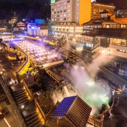 湯畑から立ち上る湯煙と夜間に美しくライトアップされた草津温泉の幻想的な光景