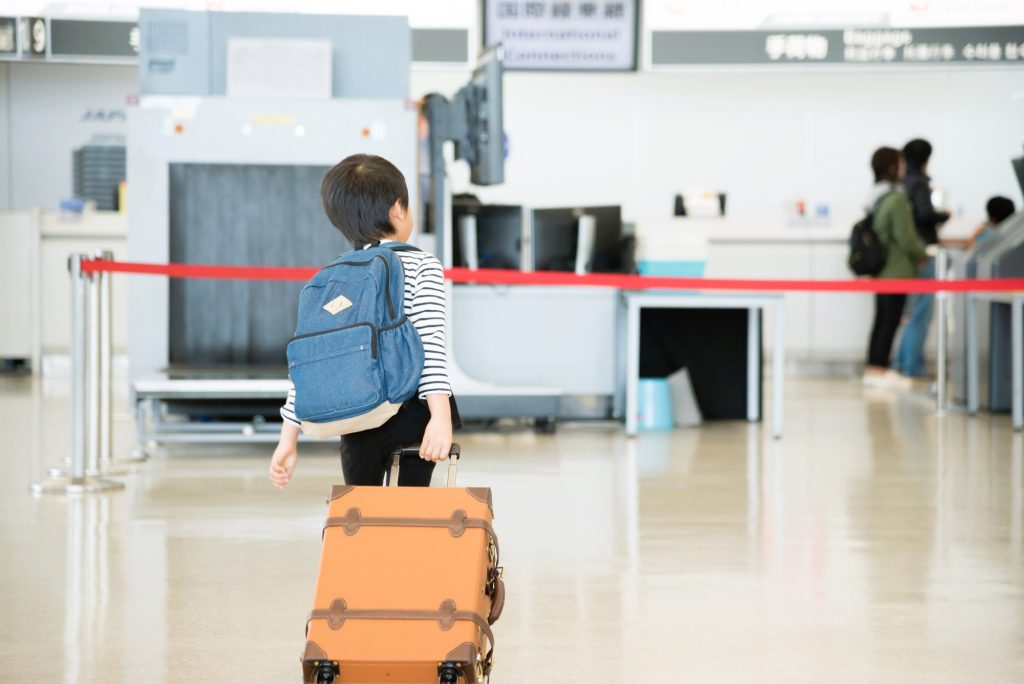空港内でスーツケースを持つ男の子